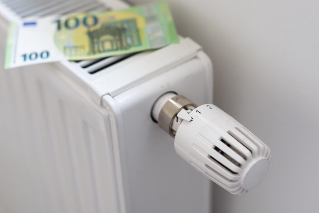 Heizkörper mit Thermostat, auf dem zwei 100-Euro-Scheine liegen