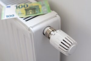 Heizkörper mit Thermostat, auf dem zwei 100-Euro-Scheine liegen