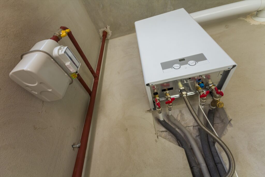 Weiße Gastherme an einer Wand, daneben ein Gaszähler und Kupferrohre