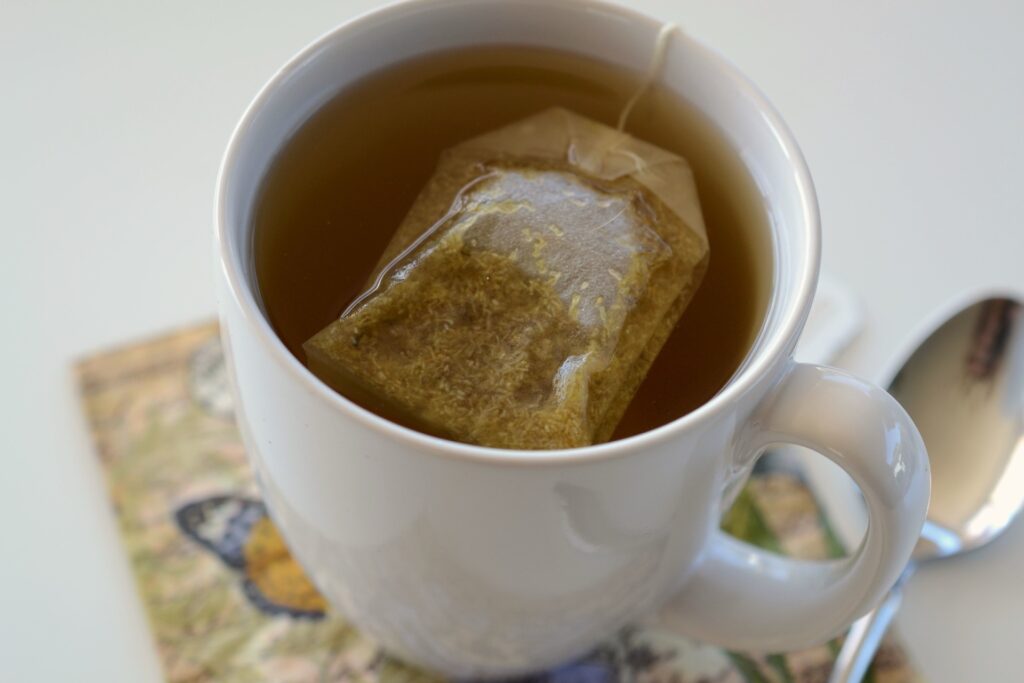 Weiße Tasse mit heißem Kräutertee, in der ein Teebeutel an der Schnur hängt
