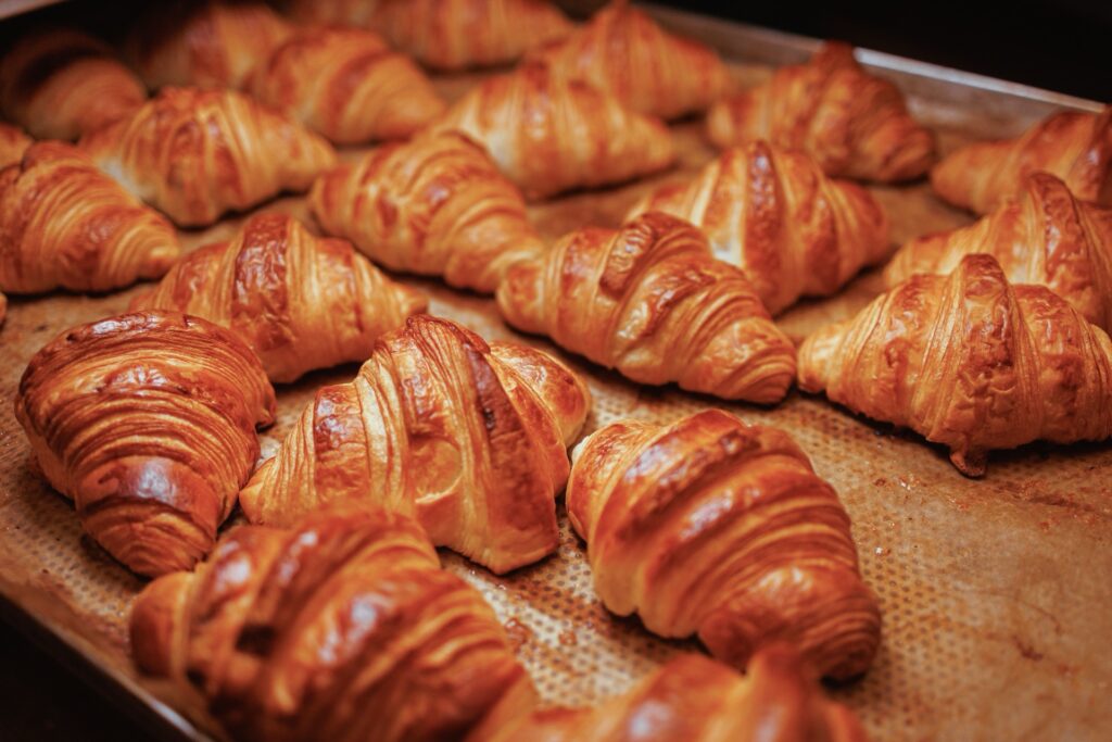 Frisch gebackene Croissants liegen dicht nebeneinander auf einem Backblech