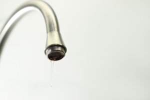 Ein silberner Wasserhahn, aus dem nur noch ein dünner Wasserstrahl tropft